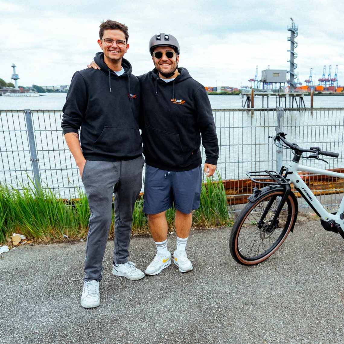 Zwei Männer neben einem Fahrrad mit der Elbe im Hintergrund | Rad und Tat